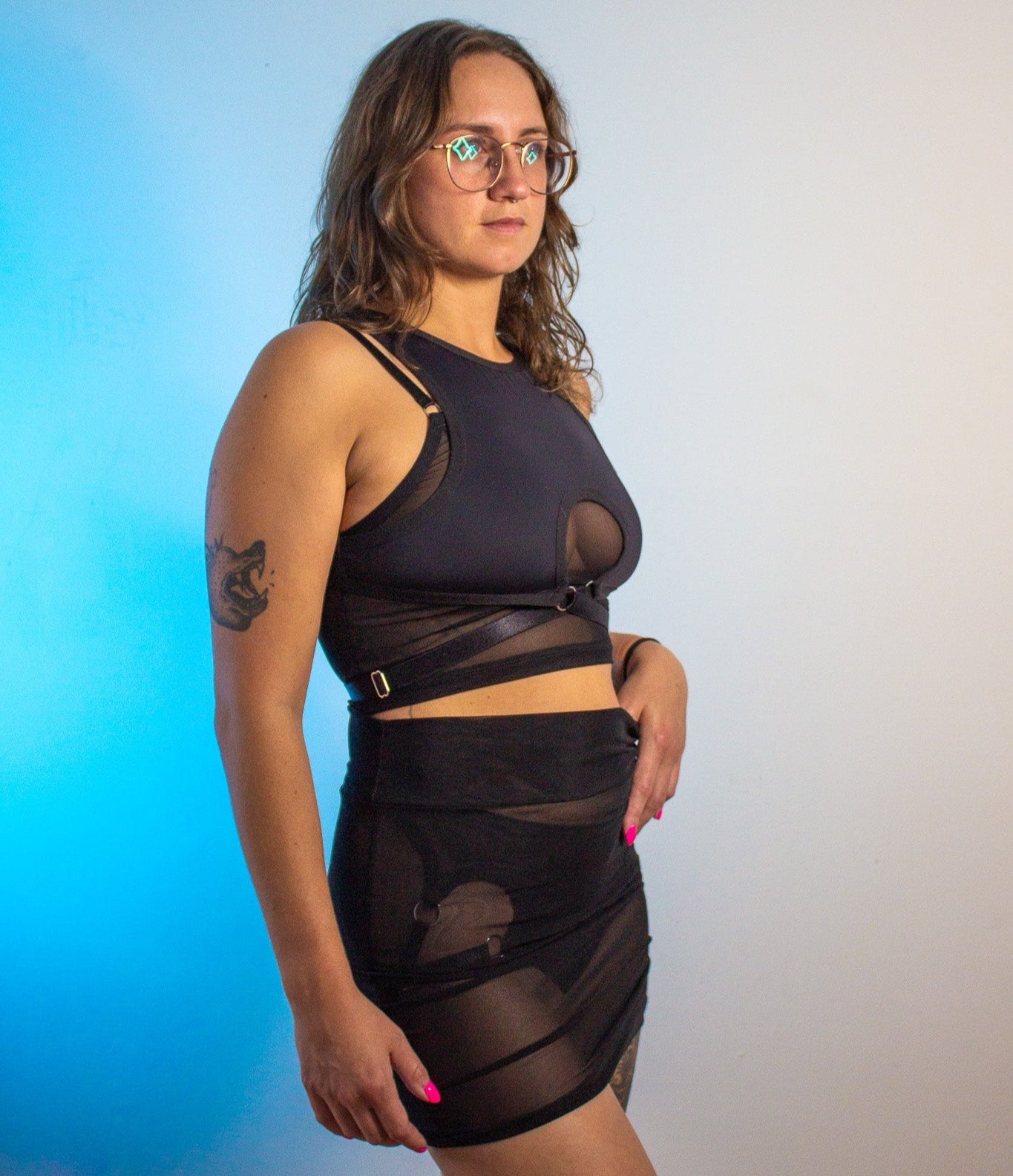 Woman wearing a black outfit with sheer details against a gradient background